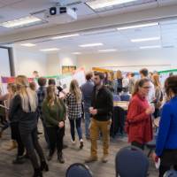 Attendees chat while viewing students' poster presentations.